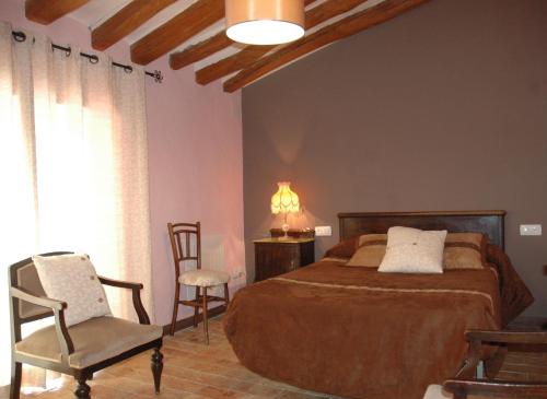 a bedroom with a bed and a chair and a window at Albergue Ull de Canals in Banyeres de Mariola