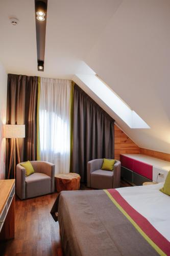 a hotel room with a bed and two chairs at Трипільське Сонце in Podgortsy