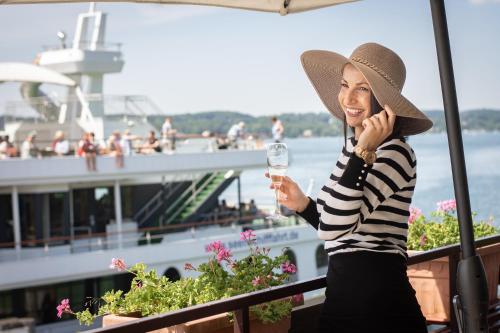 a woman holding a glass of wine on a cruise ship at Seehotel Leoni in Berg am Starnberger See