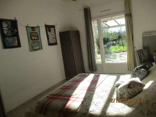 a bedroom with a bed and a sliding glass door at chambres d'hôtes "DINEDORT" in LʼAiguillon-sur-Vie