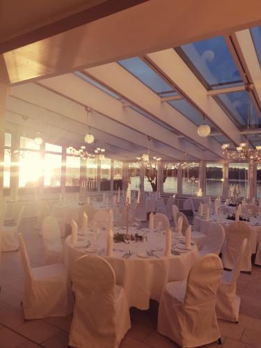 a large banquet hall with white tables and chairs at Seehotel Leoni in Berg am Starnberger See