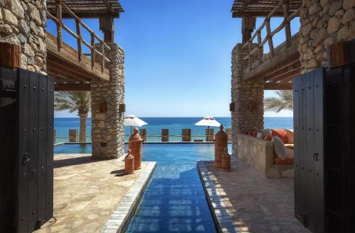 a resort with a pool and the ocean in the background at Six Senses Zighy Bay in Dibba