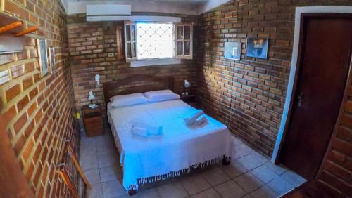 a bedroom with a bed and a brick wall at Real Pousada in Porto De Galinhas