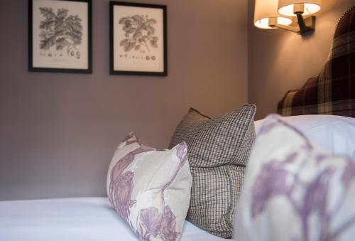 a bed with two pillows and two pictures on the wall at The Lygon Arms - an Iconic Luxury Hotel in Broadway