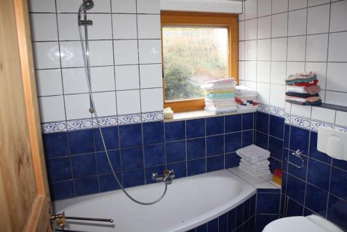 a blue and white bathroom with a tub and a window at Ferienwohnung Weilerbach in Weilerbach