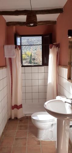 a bathroom with a toilet and a sink and a window at Alojamiento Rural ERMITA SAN JULIAN in Burunchel