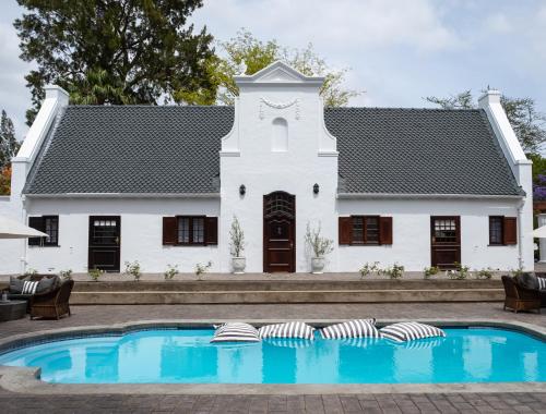 a white house with a swimming pool in front of it at Stellenhof Guest House in Addo