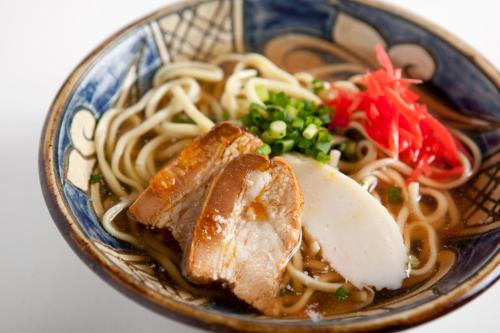 a bowl of food with noodles and meat and vegetables at Almont Hotel Naha Kenchomae in Naha