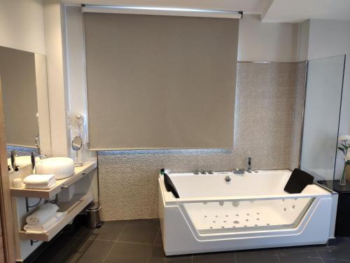 a bathroom with a tub and a sink at Hotel Puerta del Arco in Tudela de Duero