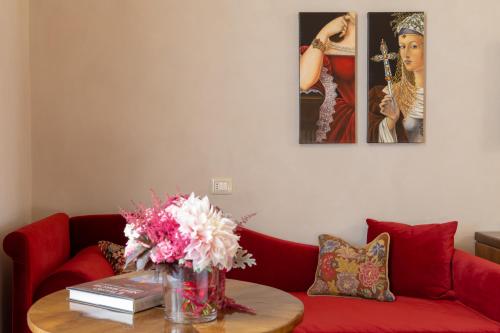 a living room with a red couch and a table with flowers at Dimora Storica Lo Svevo in Iesi