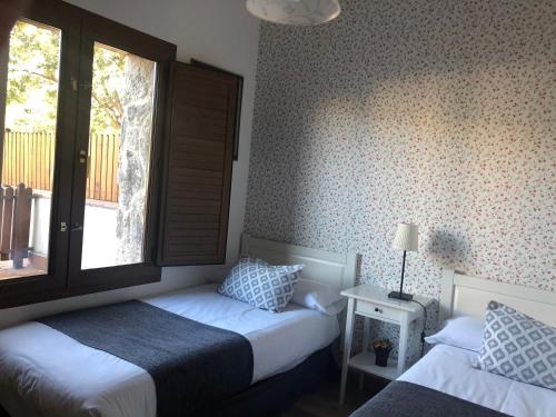a bedroom with two beds and a window at Casa de Navalhorno Valsain in La Pradera de Navalhorno