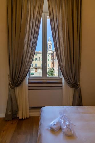 a bed with two pairs of shoes in front of a window at Dimora Storica Lo Svevo in Iesi