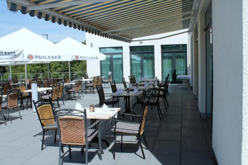 an outdoor patio with tables and chairs and umbrellas at Best Western Queens Hotel Pforzheim-Niefern in Pforzheim