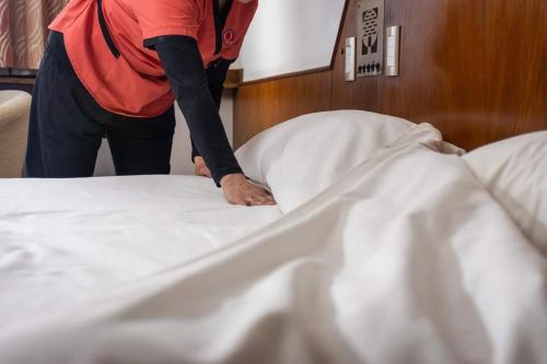 a person is making a bed in a room at Quintana Hotel in San Luis