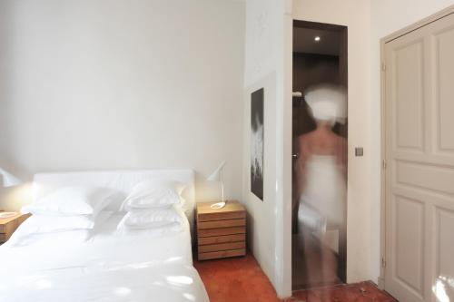 a bedroom with a white bed and a person in a closet at Maison Dauphine in Aix-en-Provence