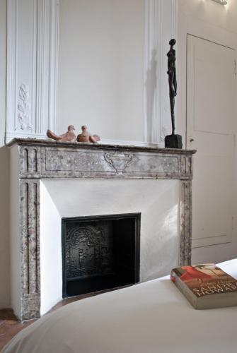 a fireplace in a white room with a book on a bed at Maison Dauphine in Aix-en-Provence