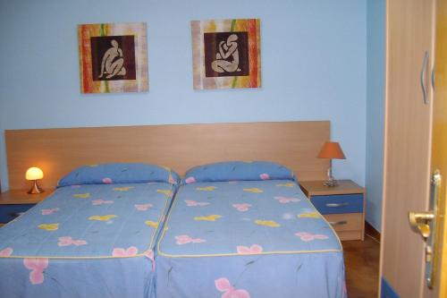 Un dormitorio con una cama azul con flores rosas. en Hospedaje Argoños, en Argoños