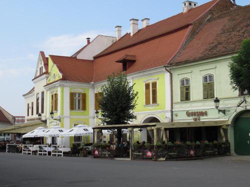 a yellow and white building with tables and umbrellas at Ferdinand Apartments in Mediaş