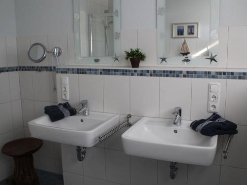 a white bathroom with two sinks and a mirror at Reetdachhaus Windsbraut in Breege