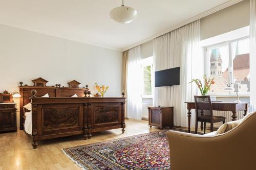 a bedroom with a large wooden bed and a desk at Dom Hotel in Augsburg