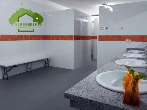 een badkamer met 4 wastafels en een aanrecht met een bord bij Albergue Puntagorda in Puntagorda