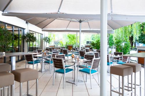 un ristorante con tavoli e sedie sotto un ombrellone di Olymp Munich a Eching