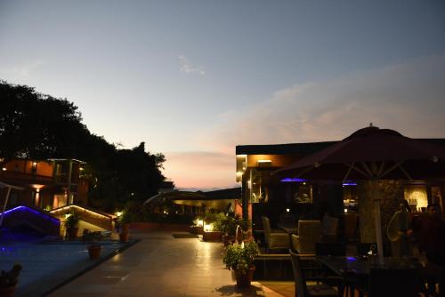 a patio with chairs and an umbrella at sunset at Brightland Resort & Spa in Mahabaleshwar
