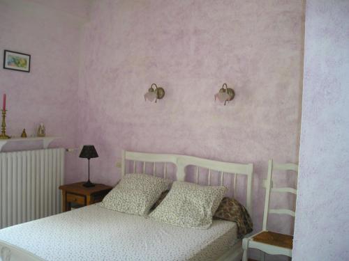 een slaapkamer met een wit bed en roze muren bij GITE MAMIE LAURENCE in Gruissan