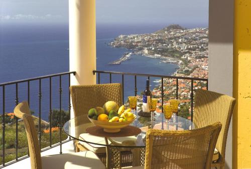 a table with a bowl of fruit on a balcony at Luxury One Bedroom Palheiro Village by Holiday Rental Madeira in Funchal