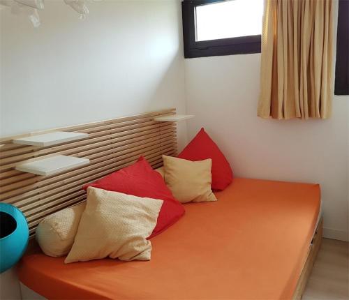 an orange bed with red and white pillows on it at Réf 541,Seignosse Océan, Appartement 3 pièces, proche de la plage et des commerces, 4 personnes in Seignosse