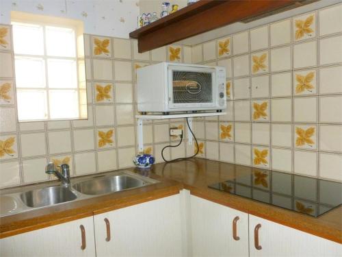 une cuisine avec un évier et un micro-ondes dans l'établissement Réf 210 Seignosse Océan, Villa Patio Classée 3 étoiles au Calme, Proche de la plage et des commerces, à Seignosse