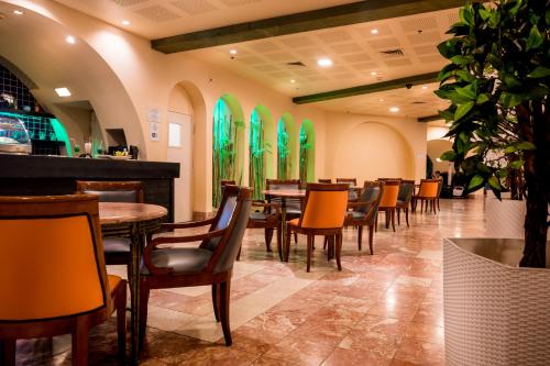 un restaurante con mesas, sillas y ventanas verdes en Club In Eilat Resort - Executive Deluxe Villa With Jacuzzi, Terrace & Parking, en Eilat