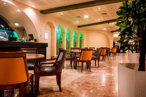 a restaurant with tables and chairs and green windows at Club In Eilat Resort - Executive Deluxe Villa With Jacuzzi, Terrace & Parking in Eilat