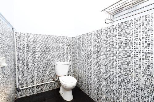 a bathroom with a toilet in a tiled wall at Griya Sakura Syariah in Solo