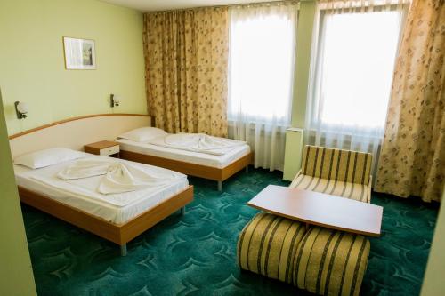 a hotel room with two beds and a chair at Struma Hotel in Pernik