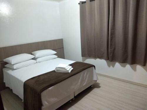 1 dormitorio con 1 cama con sábanas y almohadas blancas en Casa Das Fontes - Centro, en Gramado