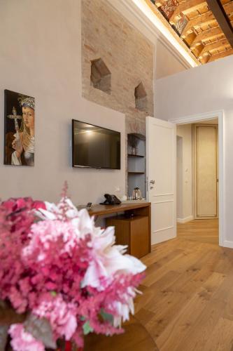 a living room with a flat screen tv and flowers at Dimora Storica Lo Svevo in Iesi