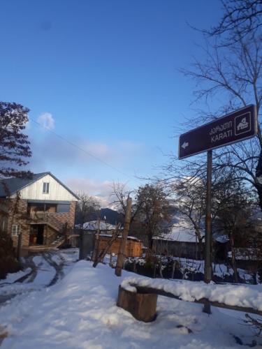 a street sign in the snow next to a house at Guest House Karati in Khulo
