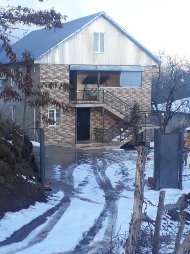 une maison en briques avec une terrasse couverte dans la neige dans l'établissement Guest House Karati, à Khulo