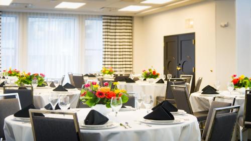 a dining room with tables and chairs with flowers on them at Hotel Indigo - Kansas City Downtown by IHG in Kansas City