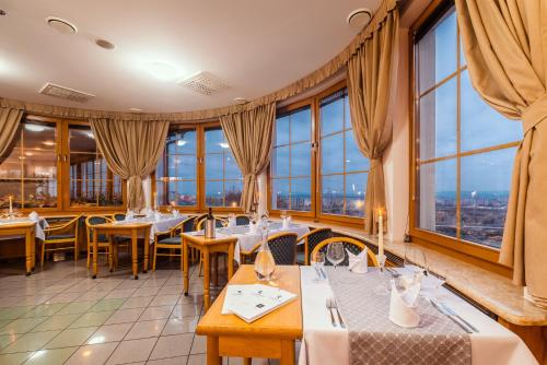 een restaurant met tafels, stoelen en ramen bij Hotel Velká Klajdovka in Brno