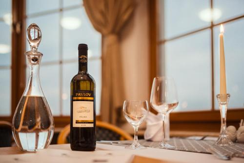 a bottle of wine sitting on a table with glasses at Hotel Velká Klajdovka in Brno