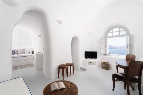 a living room with a table, chairs and a tv at Oia Spirit Boutique Residences in Oia