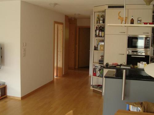 a living room with a wooden floor and a kitchen at Sot Spondas 15 in Savognin