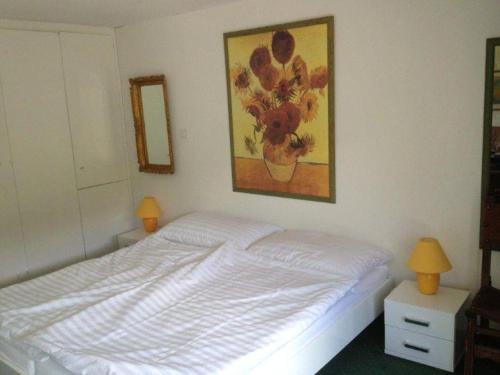 a bedroom with a white bed and a painting on the wall at Haus Viols 54 in Savognin