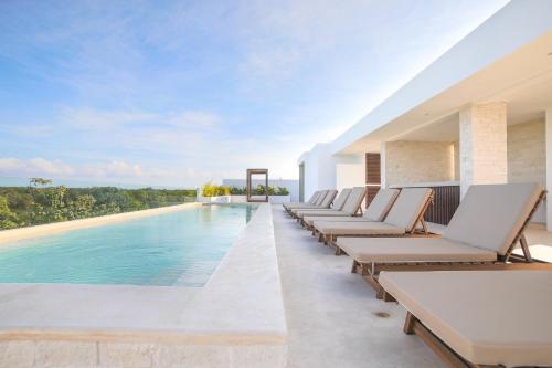 a row of lounge chairs next to a swimming pool at Hotel Blanco Tulum in Tulum