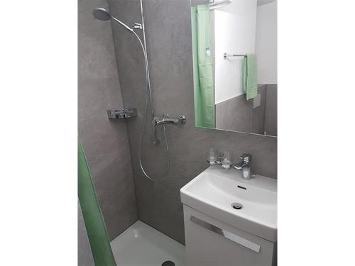 ein Bad mit einer Dusche, einem Waschbecken und einem Spiegel in der Unterkunft Tga Mucki in Savognin