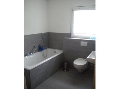 a bathroom with a tub and a toilet and a sink at Canetel 11 Whg 3 in Savognin