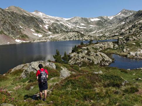 un hombre con una mochila de pie en una colina con vistas a un lago en Apartamento Forn de Serra, en Lladorre