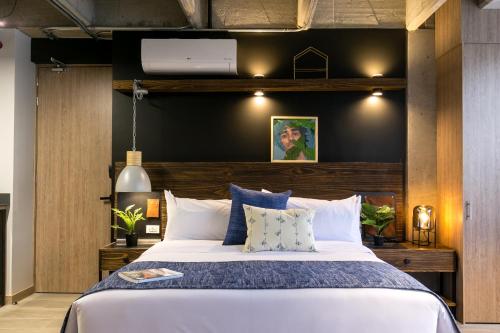 a bedroom with a large bed with blue and white pillows at Factory Lofts Hotel in Medellín